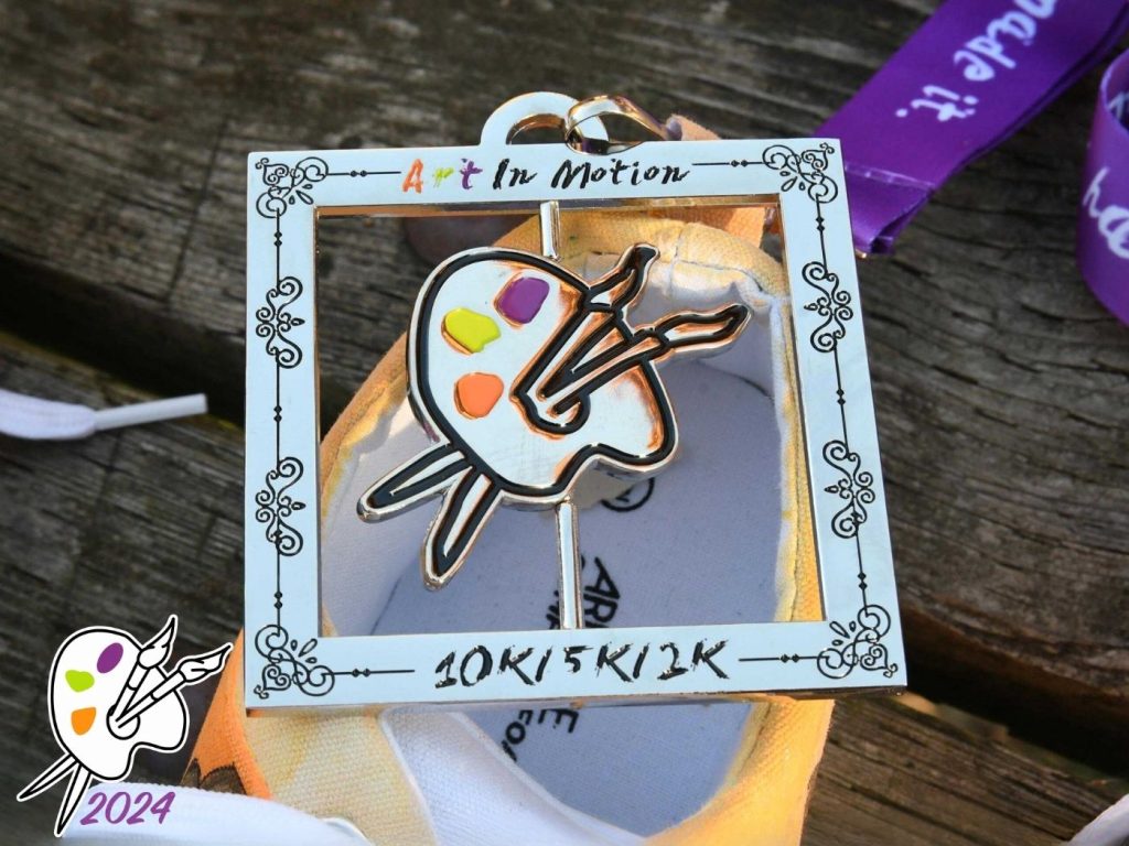 Art In Motion 2024 race medal featuring an artist palette and paintbrushes